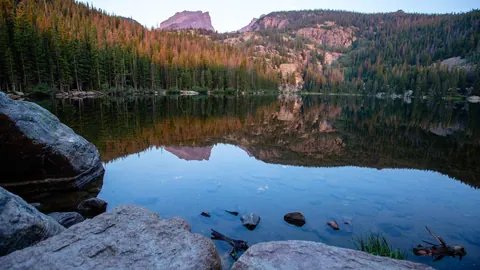Bear Lake in Rocky Mountain National Park, ringed by dense evergreen forest below a rocky peak
